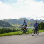 3 Fahrradfahrer bergauf vor einem Tal